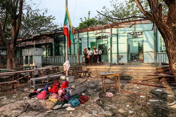 أشخاص خارج مبنى مدرسة قصفه الجيش مستهدفاً مسلّحين متمردين بإحدى قرى ميانمار (أ.ف.ب)