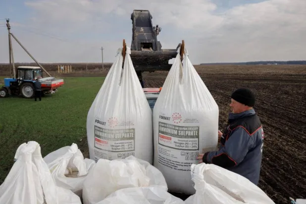 مزارع يفرغ سماداً أوكرانياً من شاحنة لاستخدامه في حقل قمح بالقرب من قرية ياكوفليفكا (رويترز)