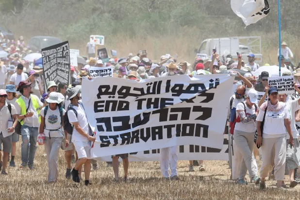 يهود وعرب في مسيرة من تل أبيب إلى الحدود مع غزة اليوم الجمعة للمطالبة بإنهاء الحرب في القطاع والإفراج عن الرهائن (إ.ب.أ)