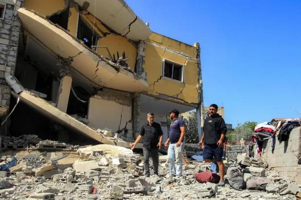 مواطنون يعاينون منازلهم التي تضررت جراء القصف الإسرائيلي على عين قانا بجنوب لبنان مساء الخميس (أ.ف.ب)