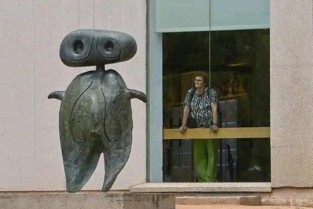 امرأة تتأمل منحوتة «شخصية» لخوان ميرو من نافذة «المؤسسة» في برشلونة (أ.ف.ب)