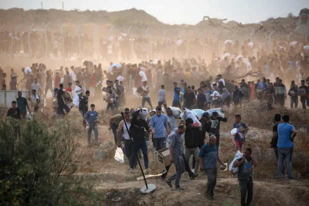 فلسطينيون يحملون معونات حصلوا عليها من مركز توزيع لـ"مؤسسة غزة الإنسانية" المدعومة أميركيا وسط قطاع غزة أمس (أ.ف.ب)