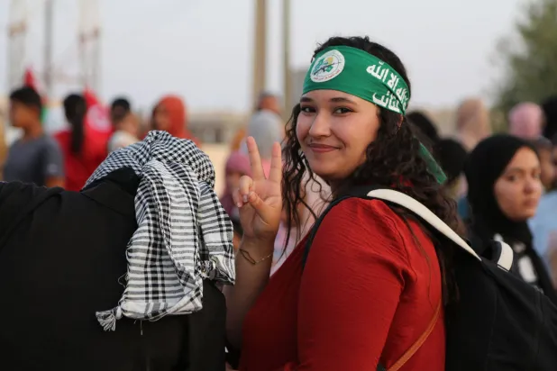 شابّة ترفع إشارة النصر بينما يرحب حشد تونسي بقافلة «الصمود» المتجهة إلى غزة براً لكسر الحصار على القطاع المتضرر من الحرب في مدينة بن قردان الساحلية جنوب شرقي تونس بالقرب من معبر رأس جدير الحدودي (أ.ف.ب)