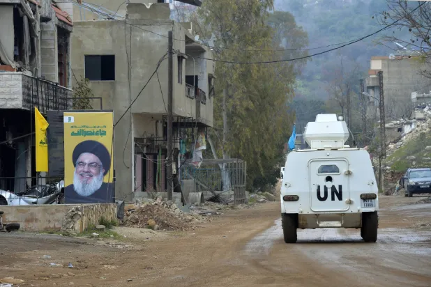 آلية تابعة لقوات «يونيفيل» في بلدة حولا حيث تظهر صورة للأمين العام السابق لـ«حزب الله» حسن نصر الله على أحد المباني (أرشيفية - إ.ب.أ)