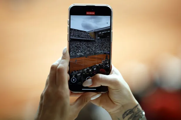 سيدة تلتقط صورة لمباراة تنس في الولايات المتحدة (إ.ب.أ)