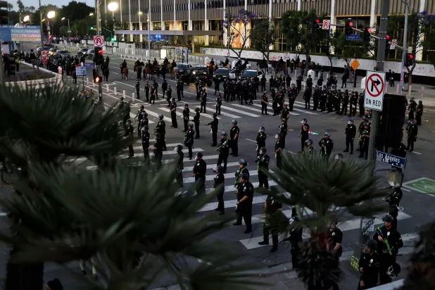 عشرات من عناصر الشرطة خلال تحرك لفرض حظر تجول في لوس أنجليس (أ.ف.ب)