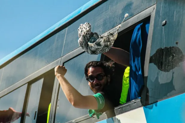 المشاركون في «قافلة الصمود» يلوّحون من حافلة (د.ب.أ)