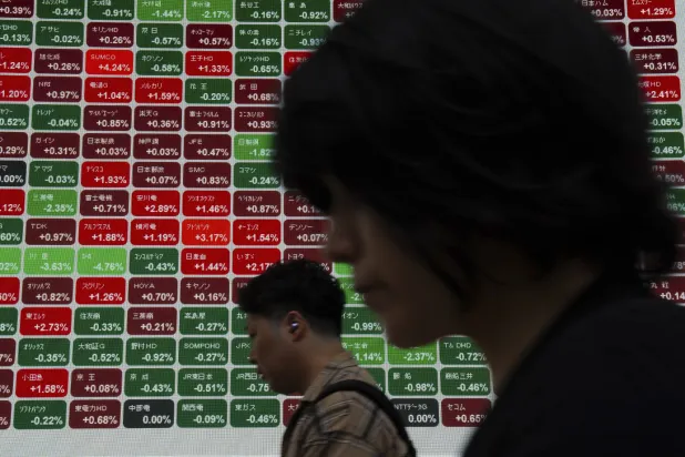 مارة أمام لوحة إلكترونية تعرض مؤشر نيكي في طوكيو (أ.ب)