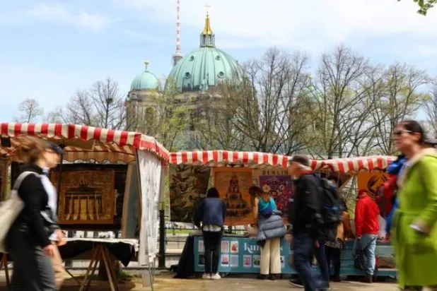 زوار في سوق الفن قرب مبنى تسويغهاوس وقبة كاتدرائية برلين (رويترز)