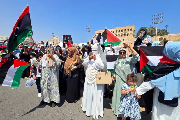 ليبيون يرحبون بالمشاركين في «قافلة الصمود» أثناء مرورها بشوارع طرابلس (أ.ف.ب)