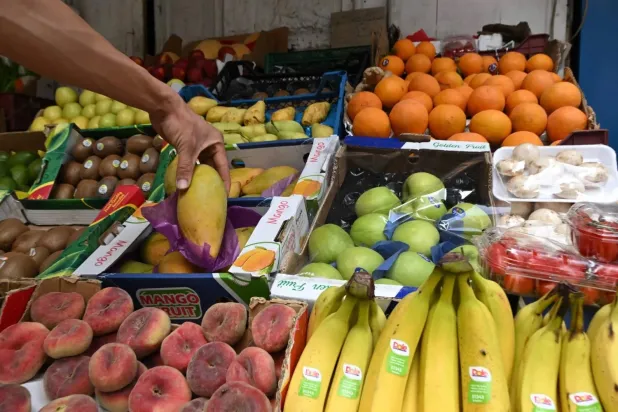 A customer inspects mangoes at a fruit stall in Damascus’s Al-Shaalan market, which now sells varieties that were unavailable during President Bashar al-Assad’s rule, such as kiwi, bananas, and pineapples. (AFP) 