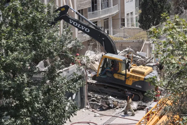 آلية تعمل على رفع أنقاض مبنى دمر في قصف إسرائيلي على طهران (رويترز) 