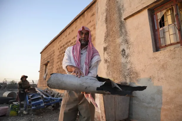 سوري يحمل جزءاً مدمراً من طائرة من دون طيار إيرانية أسقطتها الدفاعات الجوية الإسرائيلية في قرية الجبيلة جنوب سوريا الجمعة (أ.ب)
