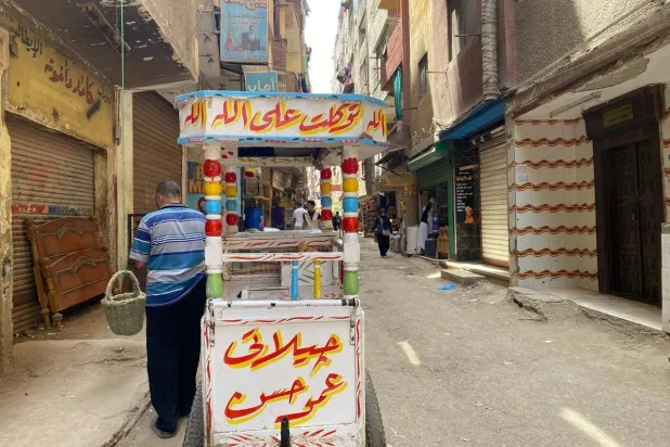 أحد الأهالي يحصل على بعض المثلجات من بائع متجول في منطقة العمرانية بالجيزة (الشرق الأوسط)