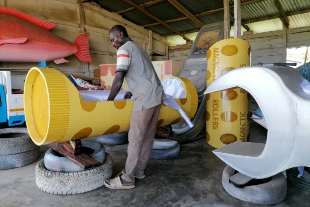 نجار يعمل على توابيت ملونة وغير عادية تُمثل حياة المتوفى (غيتي)