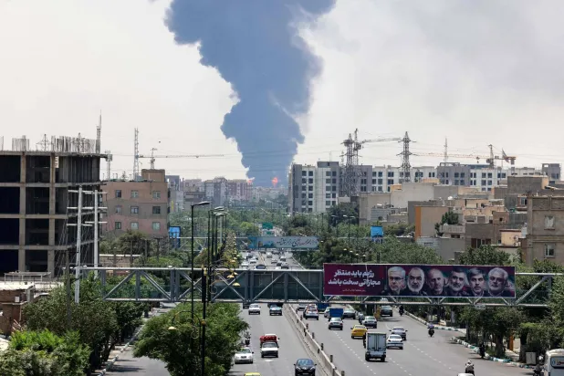 صور لقادة عسكريين إيرانيين وعلماء نوويين قُتلوا في هجوم إسرائيل بتاريخ 13 يونيو بينما يتصاعد دخان كثيف ونيران من مصفاة نفط بجنوب طهران (أ.ف.ب)