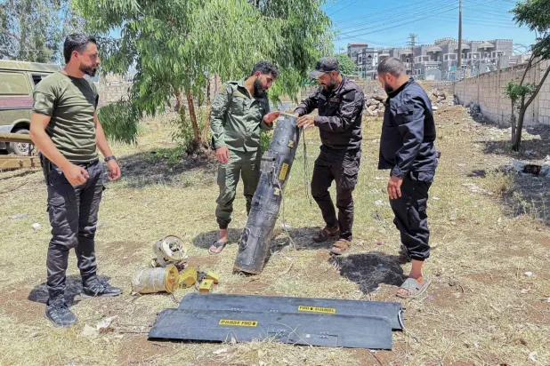 Suriye İçişleri Bakanlığı'na bağlı güvenlik görevlileri, cumartesi günü güneybatı Suriye'deki Dera yakınlarında bulunan Casim kentinde tarlaya düşen bir insansız hava aracının kalıntılarını inceliyor (AFP)