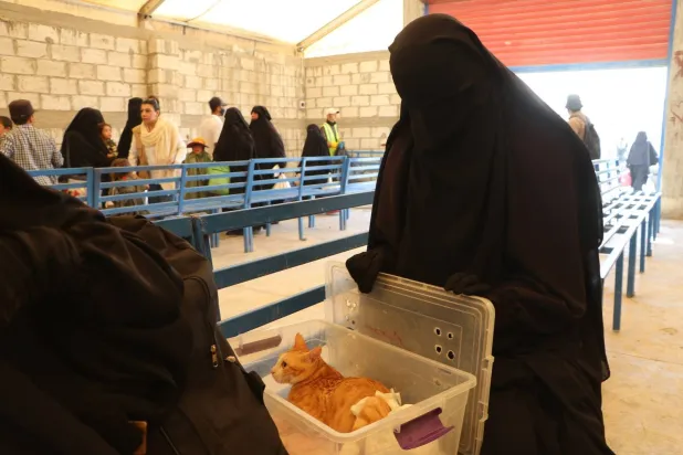 نازحة سورية من ريف حلب تحمل معها قطتها بينما تستعد لإكمال عمليات الخروج أمام إدارة مخيم الهول (الشرق الأوسط)