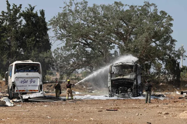 رجل إطفاء إسرائيلي يُخمد حريقًا في حافلة بموقع سقوط صاروخ إيراني في محطة حافلات في هرتسليا قرب تل أبيب (أ.ف.ب)