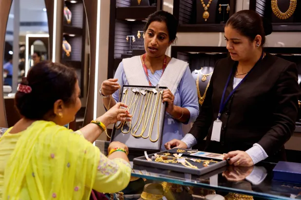 سيدة تنظر إلى سلاسل ذهبية بمتجر مجوهرات في مومباي (رويترز)