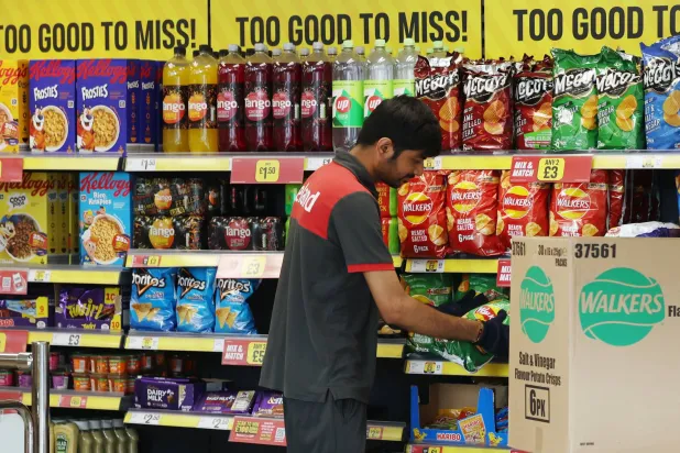 موظف بأحد المتاجر الكبرى في لندن يقوم بتعبئة الرفوف بالمواد الغذائية (إ.ب.أ)