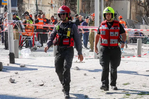 يسير رجال الإنقاذ خارج مبنى متضرر بشدة في موقع هجوم صاروخي إيراني على رامات غان وسط إسرائيل بالقرب من تل أبيب (أ.ف.ب)