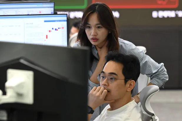 يراقب متداولو العملات أسعار الصرف في غرفة التداولات الأجنبية بمقر بنك «هانا» في سيول (أ.ف.ب)