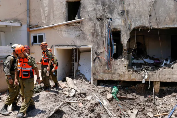 جنود إسرائيليون وفرق إسعاف أولية يتفقدون الأضرار التي لحقت بمبنى جراء غارة إيرانية على إسرائيل - 21 يونيو 2025 (أ.ف.ب)