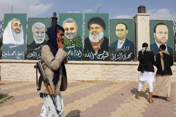 Armed Houthi supporters carry images of deceased military and political figures from Iran-aligned groups during a protest in Sanaa against Israeli airstrikes on Iran (EPA)