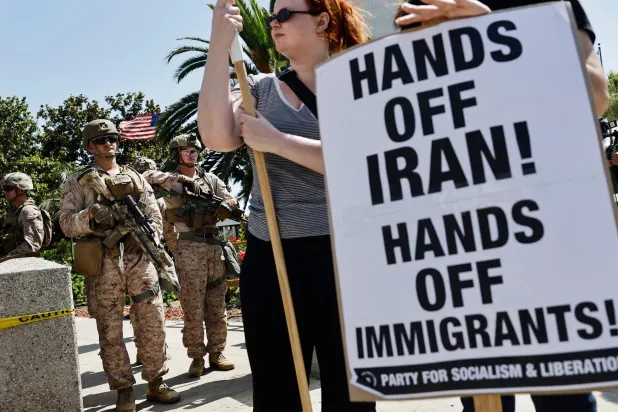  متظاهرون بالقرب من مشاة البحرية الأميركية خلال مظاهرة معارضة للضربات الأميركية على إيران في لوس أنجلوس (ا.ف.ب)
