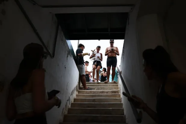 مصطافون هرعوا إلى ملجأ من القنابل في تل أبيب بعد إنذار من صواريخ إيرانية (إ.ب.أ)