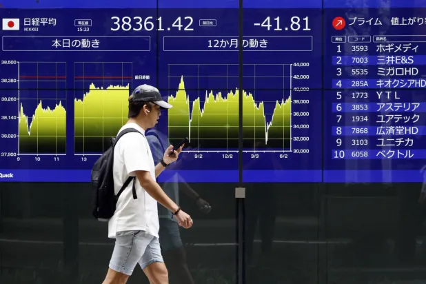 شخص يمر أمام لوحة إلكترونية تعرض حركة الأسهم وسط العاصمة اليابانية طوكيو (إ.ب.أ)