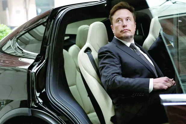 الرئيس التنفيذي لـ«تسلا» إيلون ماسك يستقل سيارة الشركة أثناء مغادرته فندقاً في بكين (رويترز)