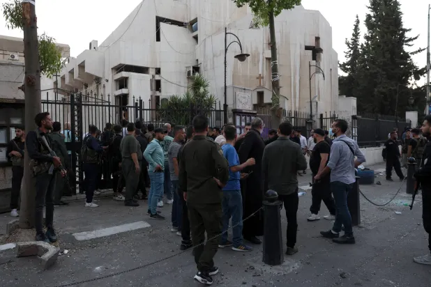 مواطنون أمام مدخل الكنيسة المستهدفة في دمشق (إ.ب.أ)