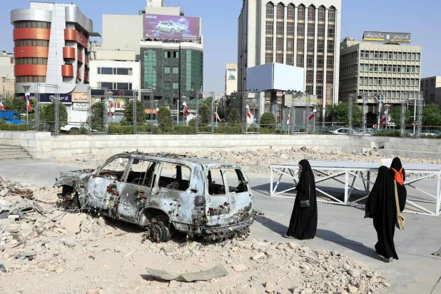 إيرانيون يتفقدون سيارة إسعاف تابعة للهلال الأحمر الإيراني دُمرت خلال غارة إسرائيلية (أ.ف.ب)