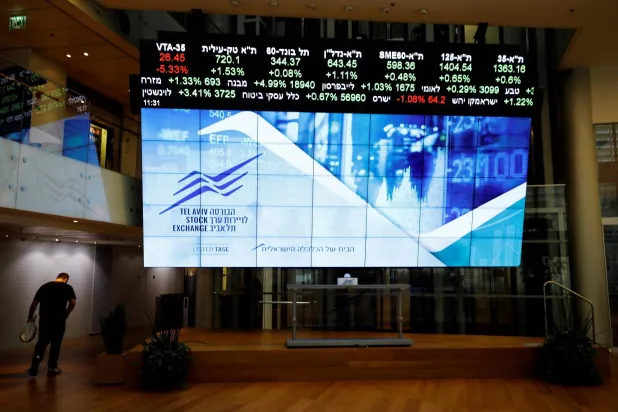 رجل يمرّ أمام لوحة تعرض بيانات السوق في بورصة تل أبيب (أرشيفية - رويترز)
