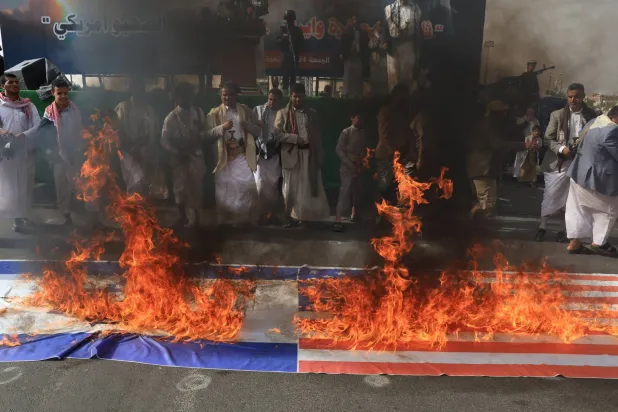 عناصر حوثيون يحرقون علمي أميركا وإسرائيل في سياق تضامن الجماعة مع إيران (إ.ب.أ)