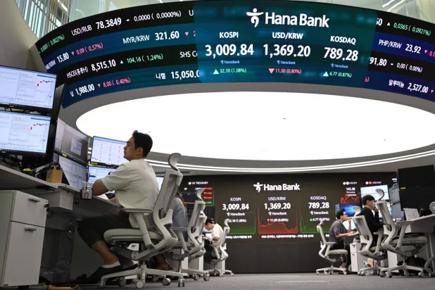 يراقب متداولو العملات أسعار الصرف تحت شاشة مؤشر «كوسبي» في بنك هانا بسيول (أ.ف.ب)