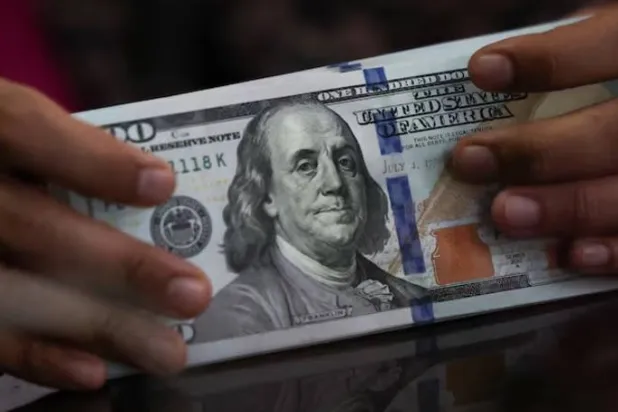 موظف يحمل أوراقاً نقدية من فئة الدولار الأميركي في مكتب صرافة بجاكرتا (رويترز)