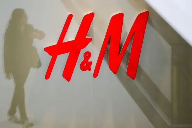 A woman is reflected next to the logo of the H&M fashion retailer in the newly opened Mall of Berlin shopping center in Berlin, Germany, in this September 25, 2014 file photo. REUTERS/Thomas Peter
