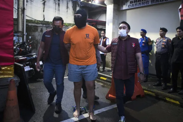 ضباط الشرطة الإندونيسية يرافقون الأسترالي إم. سي، أحد المشتبه بهم في إطلاق النار المميت على سائحة أسترالية، قبل مؤتمر صحافي في مركز الشرطة المحلي في بادونغ، بالي، إندونيسيا يوم الخميس 26 يونيو 2025 (أ.ب)