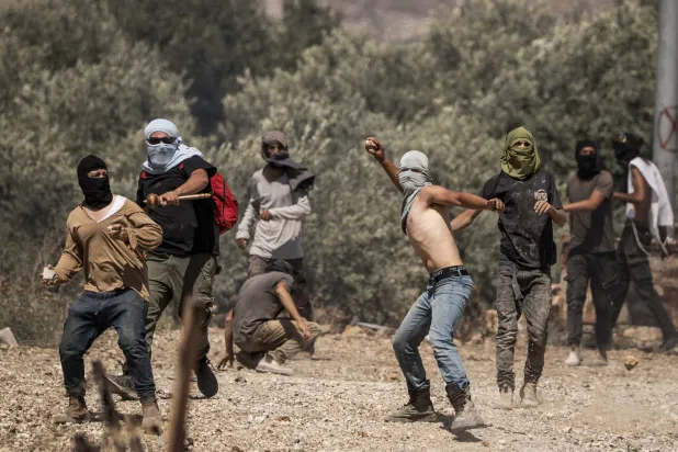مستوطنون إسرائيليون يرشقون قرويين فلسطينيين بالحجارة خلال هجوم على قرية ترمسعيا بالضفة الغربية (د.ب.أ)