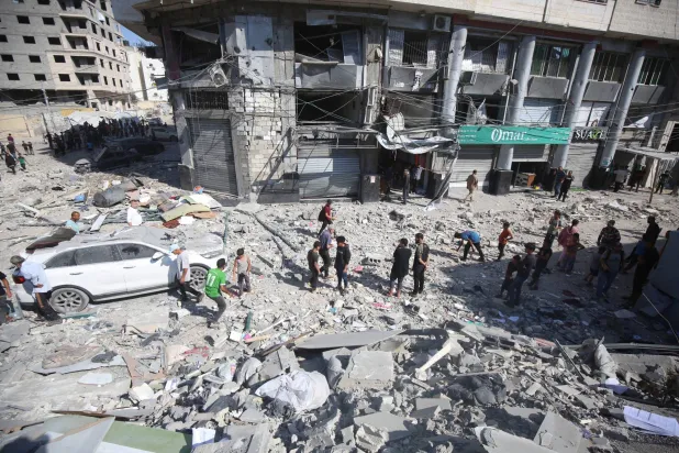 فلسطينيون وسط دمار أحدثته غارة إسرائيلية في مدينة غزة (د.ب.أ)