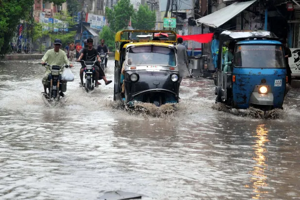 مركبات ودراجات نارية تعبر شارعاً غمرته المياه في مدينة حيدر آباد الباكستانية (إ.ب.أ)