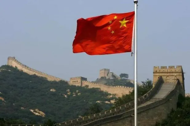علم الصين أمام سور الصين العظيم (رويترز)