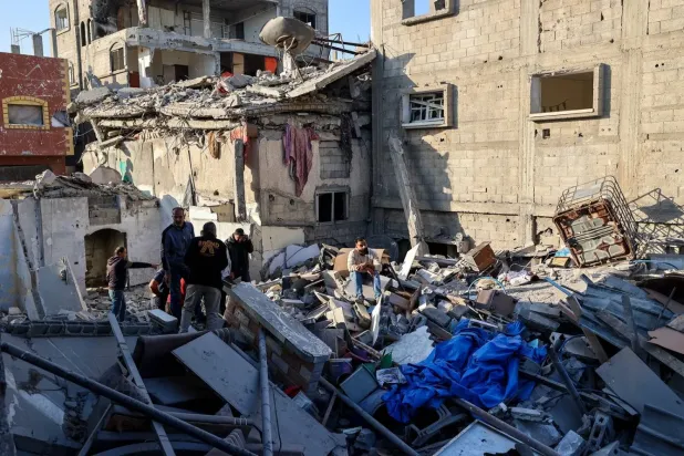 İsrail'in el-Bureyc Mülteci Kampı’na düzenlediği hava saldırısında hasar gören bir binanın enkazı arasında hayatta kalanları arayan Filistinliler (AFP)