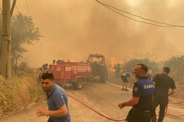 رجال الإطفاء والسكان المحليون يحاولون السيطرة على حريق غابات في منطقة مندريس بمدينة إزمير بتركيا (رويترز)