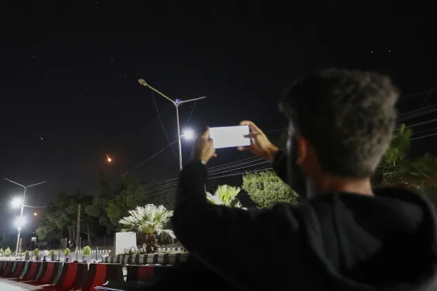 A Syrian man takes pictures with his mobile phone of Iranian missiles on their way toward Israel, as they pass over Damascus airspace, Syria, Friday, June 13, 2025. (AP) 