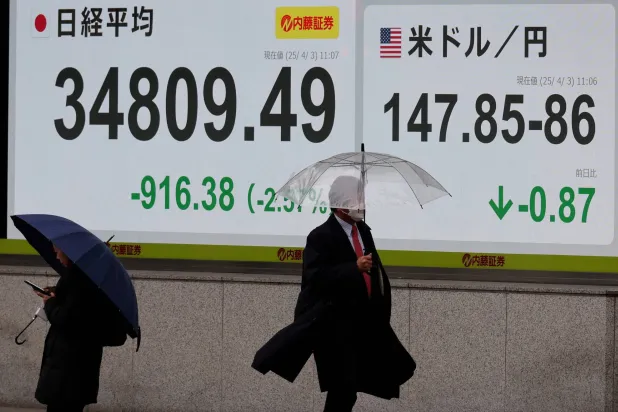 مشاة في أحد شوارع وسط العاصمة اليابانية طوكيو يمرون أمام شاشة إلكترونية تعرض حركة الأسهم (رويترز)