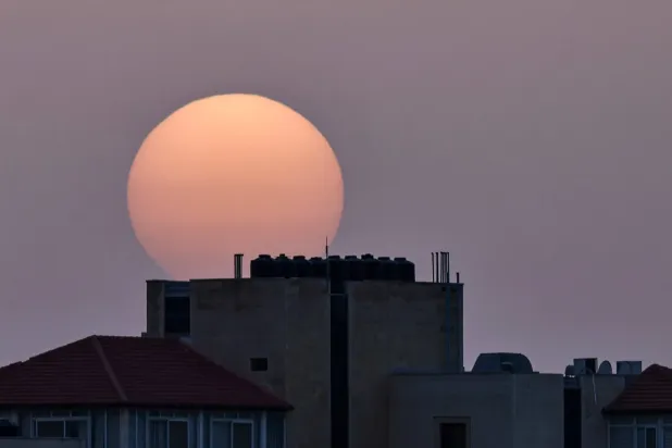 Batı Şeria'da güneş binaların ardında batarken (AFP)